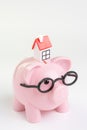 House maintenance budget, cost, savings or mortgage home loan concept, miniature house on pink piggy bank wearing glasses on white Royalty Free Stock Photo
