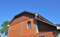 House mansard roof with brick wall, unfinished window installation, rain gutters