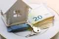 House model, a bundle of money and keys are on a white plate Royalty Free Stock Photo