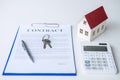 House model, calculator and house key lying on real estate contract, home loan and investment concept Royalty Free Stock Photo