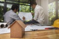 House model on desk over confident team of architects working together in a office. Architect discuss with engineer about project Royalty Free Stock Photo