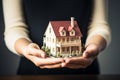 House model gently held by young woman, representing dreams taking shape