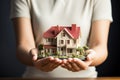 House model gently held by young woman, representing dreams taking shape