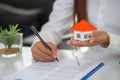 House model and keys in the hands of business people. A woman signs a contract to purchase a home with a real estate agent Royalty Free Stock Photo