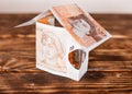 A house model made of money on wooden background