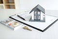 House model and Money, house key lying on real estate contract, home loan and investment concept Royalty Free Stock Photo