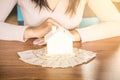 House model and money on wooden table with woman sitting in background planing to buy or rent home Royalty Free Stock Photo