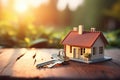 House model on a wooden tabletop. House keys on the countertop. The concept of buying, searching for housing.