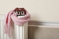 House model wrapped in pink scarf on radiator, space for text. Heating efficiency Royalty Free Stock Photo