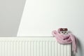 House model wrapped in pink scarf on radiator, space for text. Winter heating efficiency Royalty Free Stock Photo