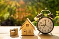 The house money coins and alarm clock stack on wood table and sunset background in the public pack and Business concept. Royalty Free Stock Photo