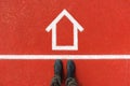 House mortgage concept, top view of man on dirty boots standing over house symbol drawn on tartan surface