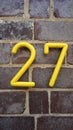 House number on the brick wall - twenty seven in yellow numerals Royalty Free Stock Photo