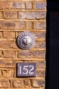 House number 152 on a brick wall under a round sun ornament Royalty Free Stock Photo