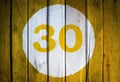 House number or calendar date in white circle on yellow toned wooden door background. Number thirty 30 Royalty Free Stock Photo