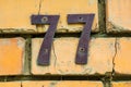House number 77 made of iron on a brick wall