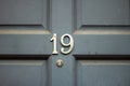 House number 19 with the nineteen in silver on a gray wooden door