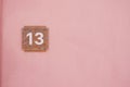 House number thirteen on a pink wall in a sunny location Royalty Free Stock Photo