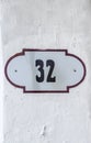 House number 32 thirty two. Black lettering on a white metal plate with brown edge Royalty Free Stock Photo