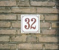 House Number 32 thirty two. brown numbers on a white plate constructed to a old brick wall Royalty Free Stock Photo