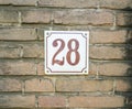 House Number 28 twenty eight. brown numbers on a white plate con Royalty Free Stock Photo