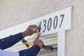 House Painter Contractor Nails Address Numbers to House Facade Royalty Free Stock Photo