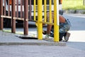 The house painter paints a fence yellow oil paint.