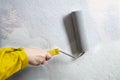 House painter paints wall gray uses paint roller with yellow handle Royalty Free Stock Photo