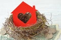 House paper with heart in nest on money background - Love for home, home insurance concept