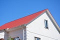 House with plaster walls, attic window, red metal roof and white plastic rain gutter. Roofing construction. Royalty Free Stock Photo