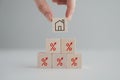 House and property investment and asset management concept. Hand holding house icon on wooden block from red percentage sign icon. Royalty Free Stock Photo