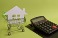 House put in a shopping cart and calculator on the desk. Savings for home, buying houses, sell houses, real estate or housing Royalty Free Stock Photo