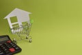 House put in a shopping cart and calculator on the desk. Royalty Free Stock Photo