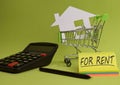 House put in a shopping cart and coin, calculator on the desk. Royalty Free Stock Photo