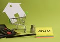 House put in a shopping cart and coin, pen, calculator on the desk. Royalty Free Stock Photo