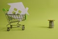 House put in a shopping cart and coins on the desk. Royalty Free Stock Photo