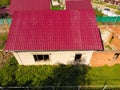 A house with a red roof made of corrugated metal sheets. Roof from corrugated metal profile. Metal tiles. Royalty Free Stock Photo