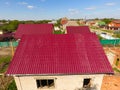 A house with a red roof made of corrugated metal sheets. Roof from corrugated metal profile. Metal tiles. Royalty Free Stock Photo