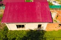 A house with a red roof made of corrugated metal sheets. Roof from corrugated metal profile. Royalty Free Stock Photo