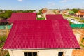 A house with a red roof made of corrugated . Roof from corrugated metal profile. Metal tiles Royalty Free Stock Photo