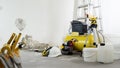 House renovation concept, helmet and safety headphones, air compressor and construction tools, white wall in the background