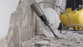 House renovation concept, wall in demolition with plaster rubble and protective construction work tools, helmet, yellow compressor