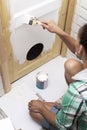 House repair. Woman sitting on the floor in the bathroom and paint wooden door with a round entrance for cats in white color with