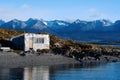 House on river with mountains at back. Royalty Free Stock Photo