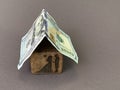 House with a roof made of hundred dollar bills. Silhouettes of lovers on a piece of wood.Concept: double house, mortgage, purchase