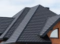 The house, the roof of which is covered with black metal tiles. Black tiles roof on a new house Royalty Free Stock Photo