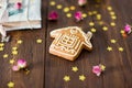 House shape ginger cookie with white glaze on brown wooden background. Golden star decoration and dry roses Royalty Free Stock Photo