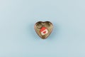 House shaped keychain with red heart in heart shaped metal box on blue background