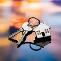 House shaped keys on reflective surface with blurred vibrant colors, symbolizing homeownership at dusk