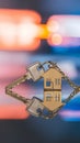 House shaped keys on reflective surface with blurred vibrant colors, symbolizing homeownership at dusk